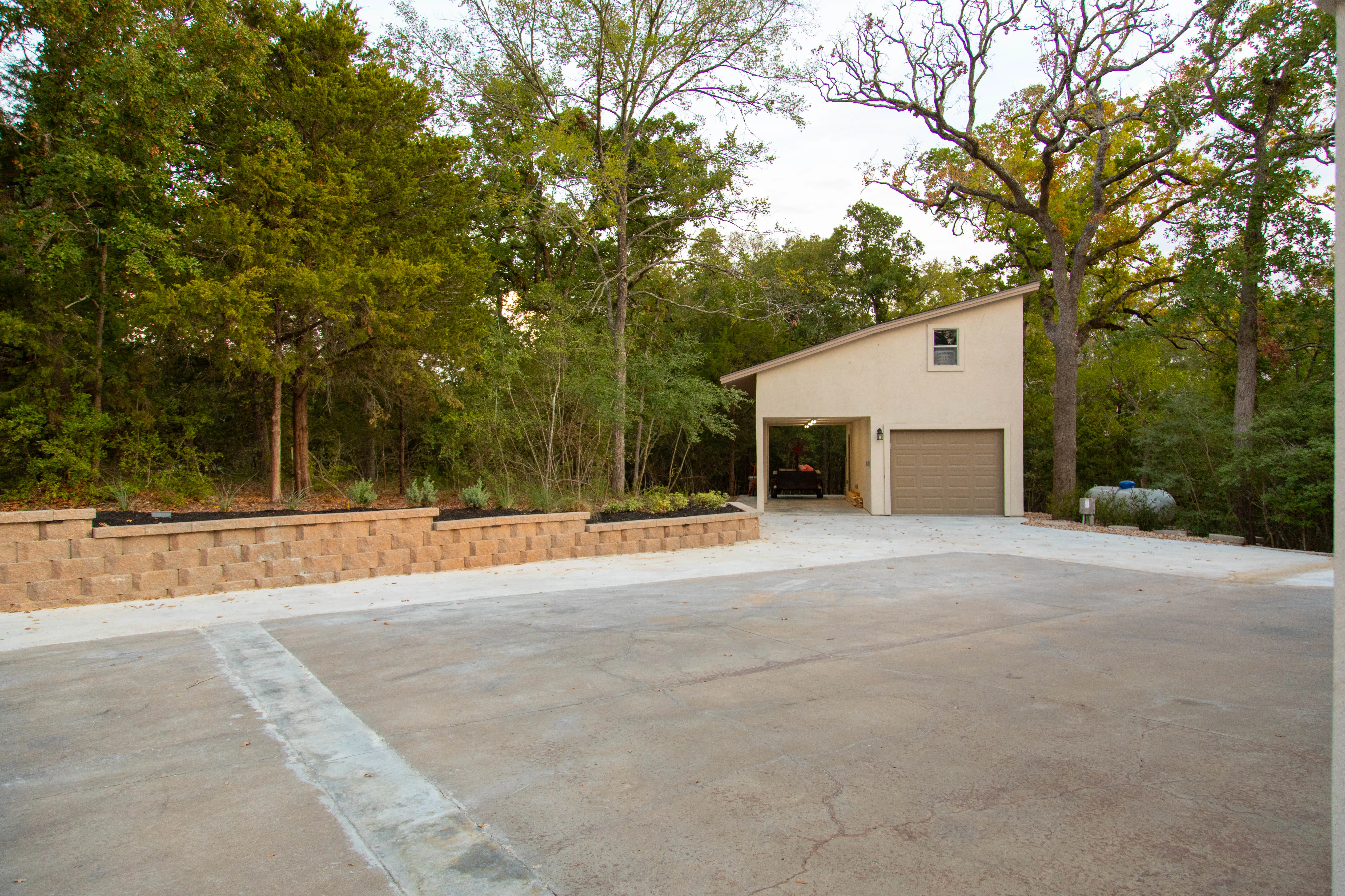 Concrete driveway with segmental retaining wall and planted beds in wooded setting
