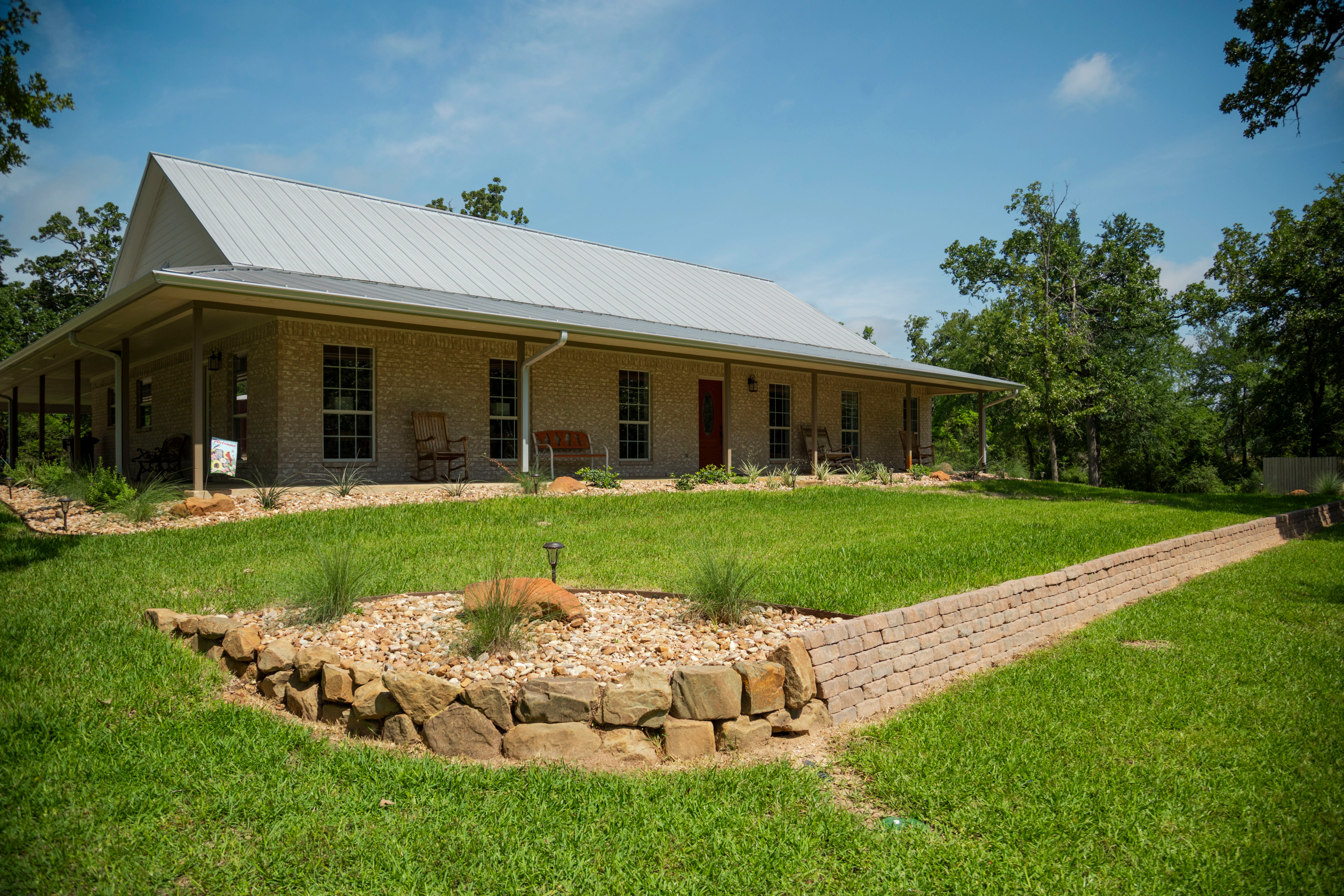 Modern brick home with manicured lawn, rock landscaping beds, and brick pathway — Landscape Contractor by Landscaping Ninjas in College Station, TX