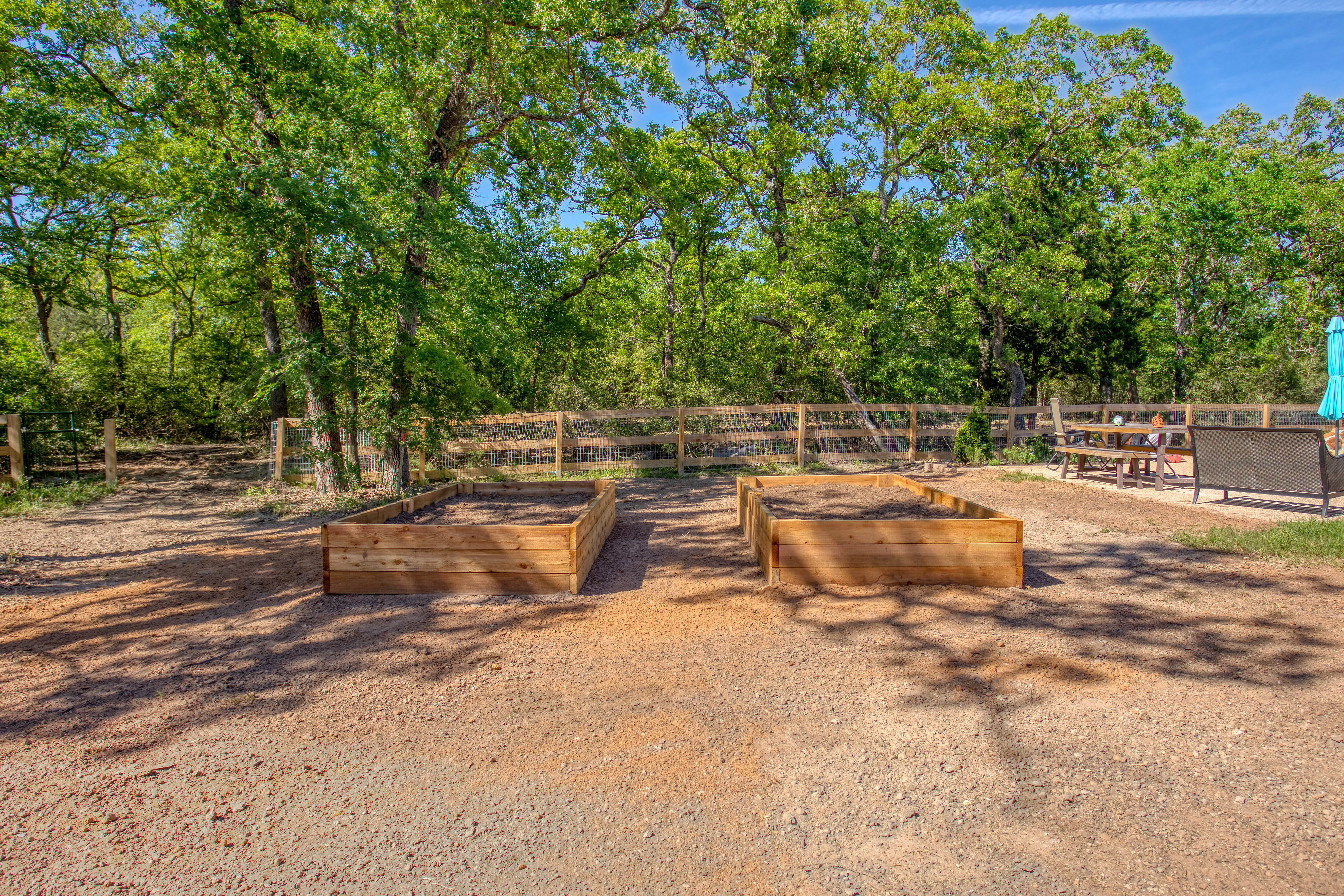 Two wooden raised garden beds with rustic fencing in wooded landscape setting