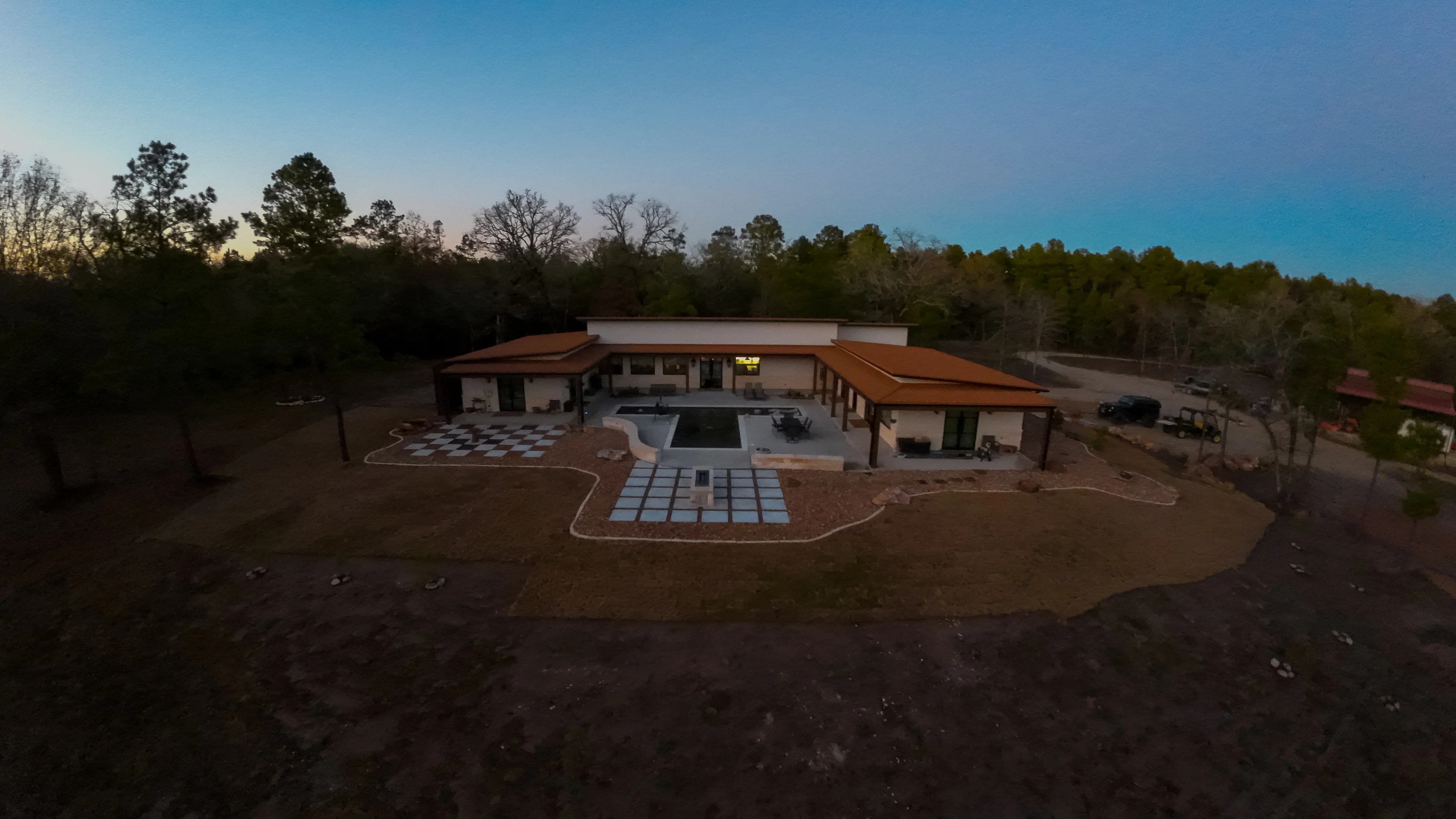 Aerial view of completed hardscape project with central fire pit, pavers, and metal-roofed structures — Masonry Contractor by Landscaping Ninjas in College Station, TX