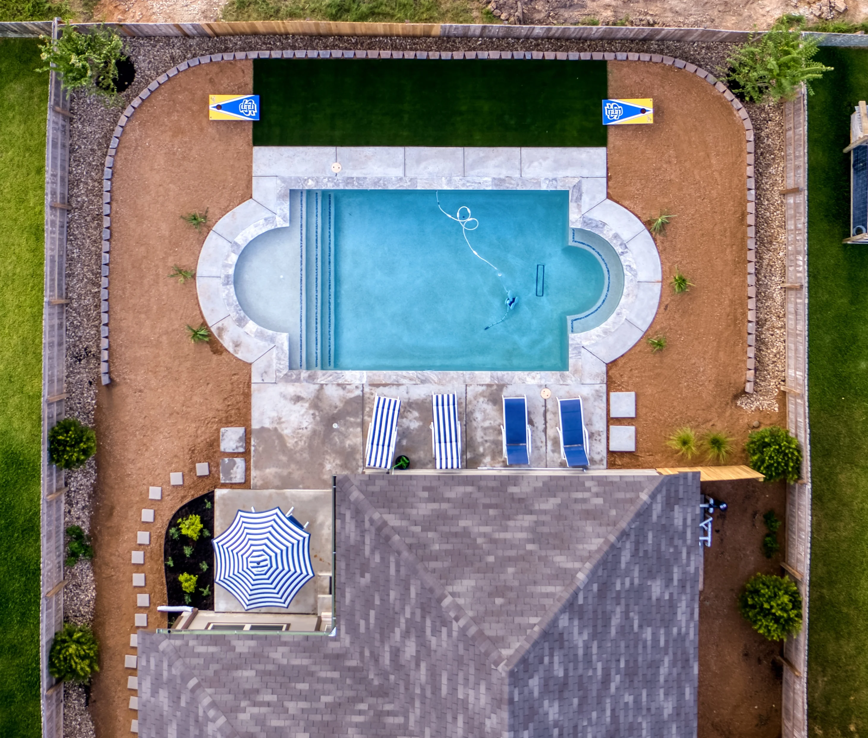 Aerial view of landscaped pool area with curved stone borders and patio seating